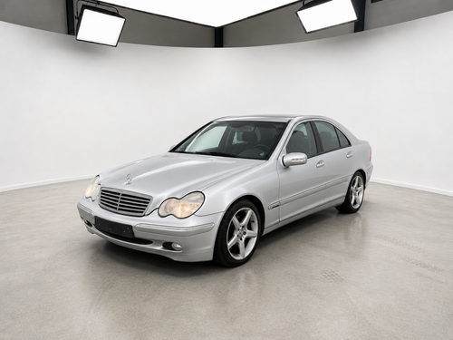 Sølvfarvet Mercedes 320 V6 sedan med alufælge fotograferet i et lyst showroom.